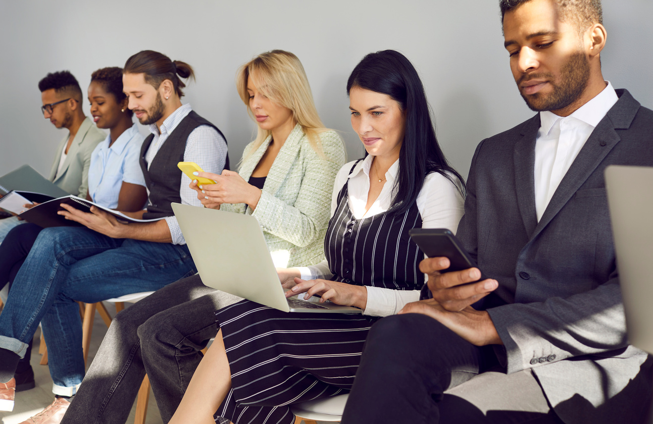 Multiracial People Using Laptops and Cellphones While Waiting in Line for Job Interview